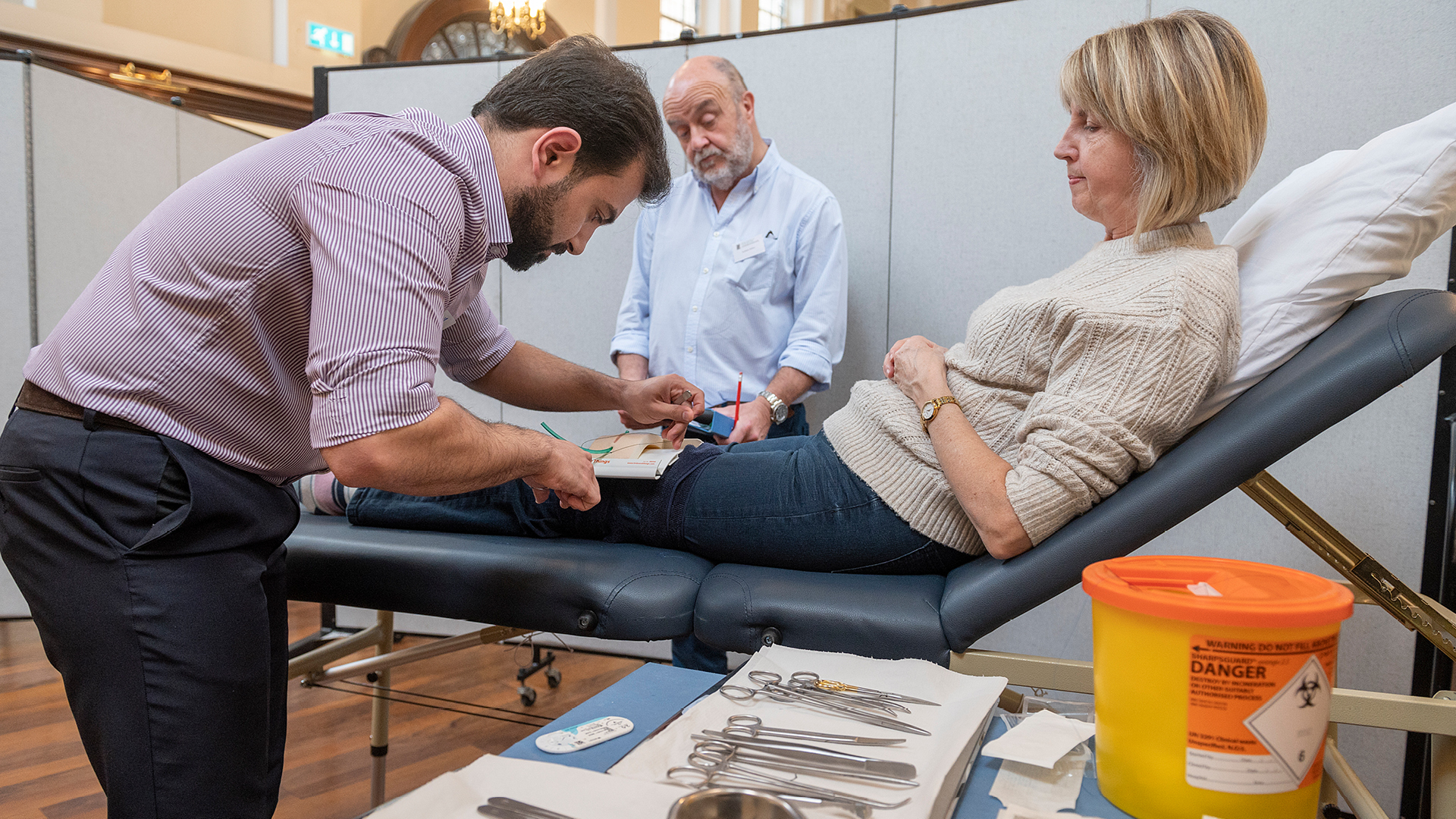 A candidate in a surgical mock exam with a patient and examiner