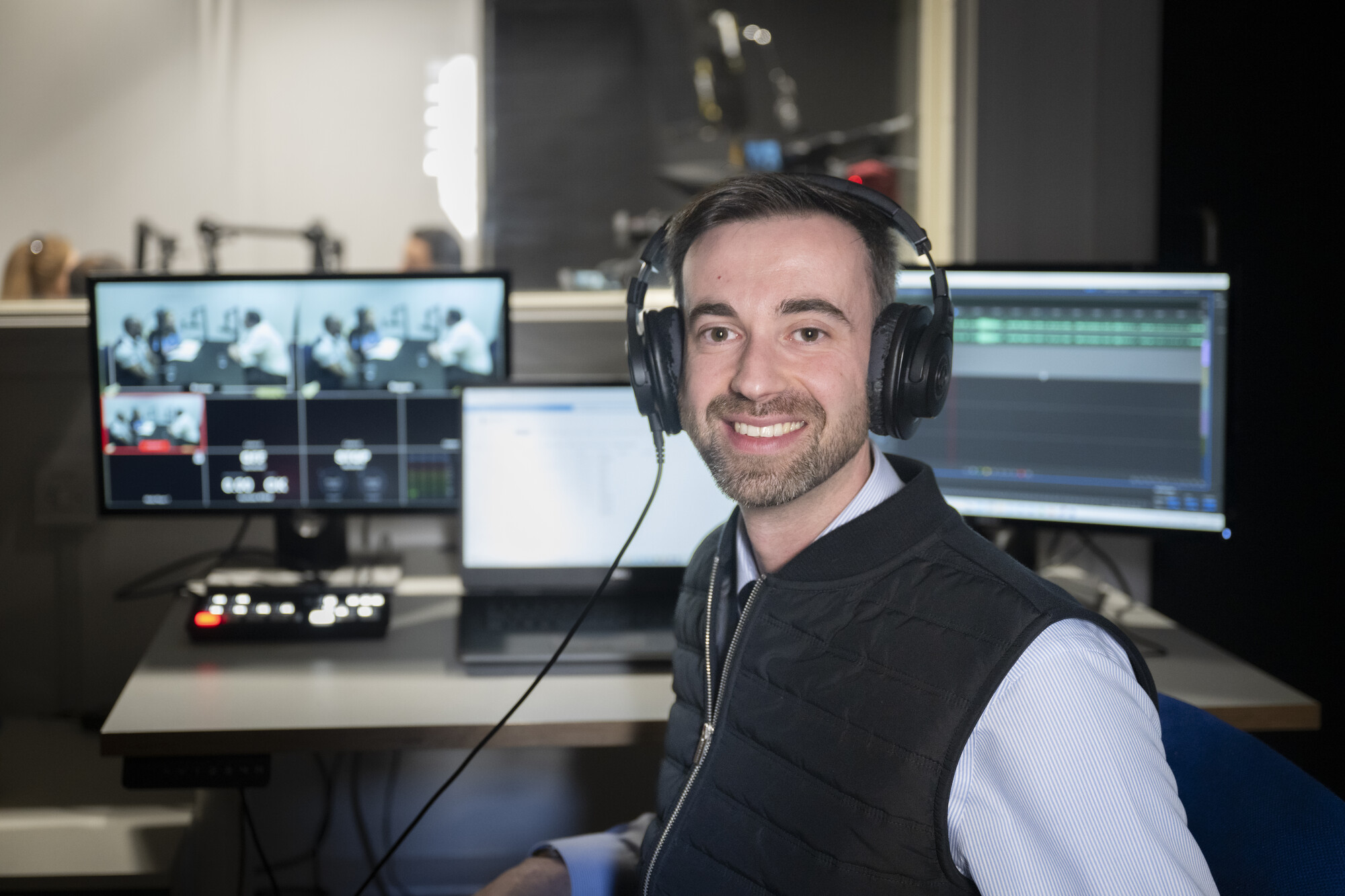 Colleague sat at a sound desk with headphones on 