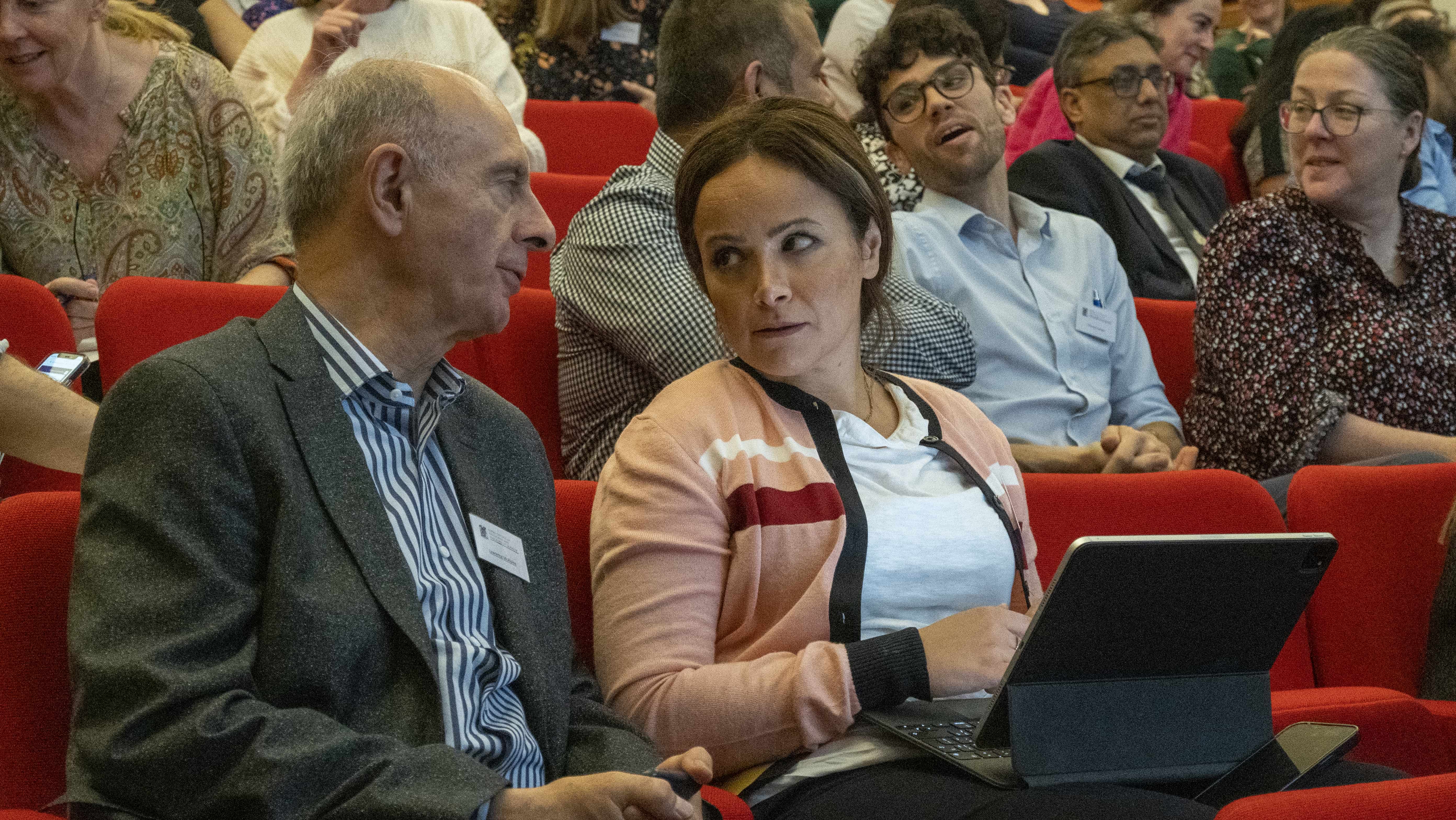 two people in a lecture theatre having a discussion